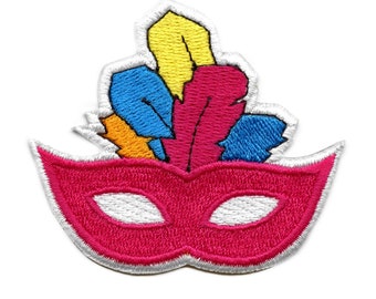 May include: A pink masquerade mask with white eye holes and a colorful feather design on top. The feathers are yellow, orange, blue, and pink.