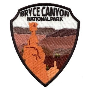 Peut inclure: Écusson brodé représentant une vue panoramique du parc national de Bryce Canyon, dans l'Utah. L'écusson a la forme d'un bouclier et est bordé de brun. Le texte "Bryce Canyon National Park" est brodé en noir sur fond blanc.