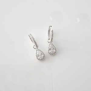 Pu&ograve; includere: Un paio di orecchini a cerchio d'argento con un ciondolo di cristallo a forma di pera. Il cristallo &egrave; circondato da cristalli pi&ugrave; piccoli.