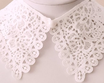 May include: White lace collar with a scalloped edge. The collar is made of delicate lace and has a vintage look.