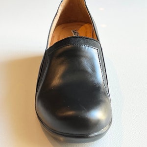 Peut inclure: Chaussures &agrave; enfiler en cuir noir avec une bande &eacute;lastique noire sur le dessus. Les chaussures ont un int&eacute;rieur en cuir marron et une semelle en caoutchouc noir.
