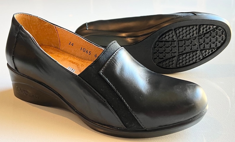 Peut inclure: Chaussures compens&eacute;es en cuir noir avec un panneau en daim noir sur le c&ocirc;t&eacute;. Les chaussures ont une semelle en caoutchouc avec un motif textur&eacute;. La taille 24 est imprim&eacute;e &agrave; l'int&eacute;rieur de la chaussure.