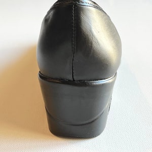 Peut inclure: Chaussure &agrave; talon en cuir noir avec bout arrondi et semelle &eacute;paisse en caoutchouc noir.