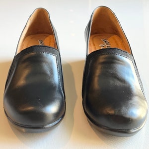 Peut inclure: Une paire de chaussures &agrave; enfiler en cuir noir avec des inserts &eacute;lastiques. Les chaussures ont une pointe arrondie et un talon bas.