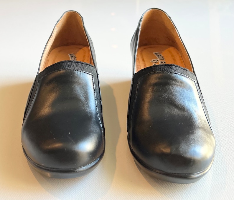 Peut inclure: Une paire de chaussures &agrave; enfiler en cuir noir avec des inserts &eacute;lastiques. Les chaussures ont une pointe arrondie et un talon bas.