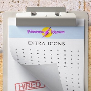 May include: A white clipboard with a red stamp that says "HIRED" on it. The clipboard has a sheet of paper with the text "Feminine Resume" and "EXTRA ICONS" on it. The paper has a grid of small black icons.