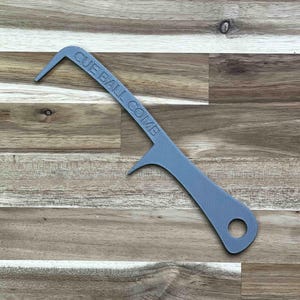 May include: A gray cue ball comb with the text "CUE BALL COMB" printed on the curved handle. The comb has a hook on one end and a small projection on the other. A hole is at the end of the handle.