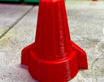 May include: A bright red wire connector with two side wings. The connector has a ribbed design and is made of plastic.
