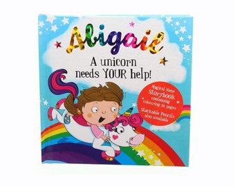 May include: A personalized children's storybook with a rainbow and a unicorn on the cover. The book is titled "Abigail, A unicorn needs YOUR help!" and features a magical name storybook containing coloring pages. Stackable pencils are also available.