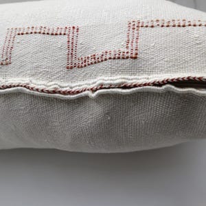 May include: White pillow with a red geometric design and a zipper closure.