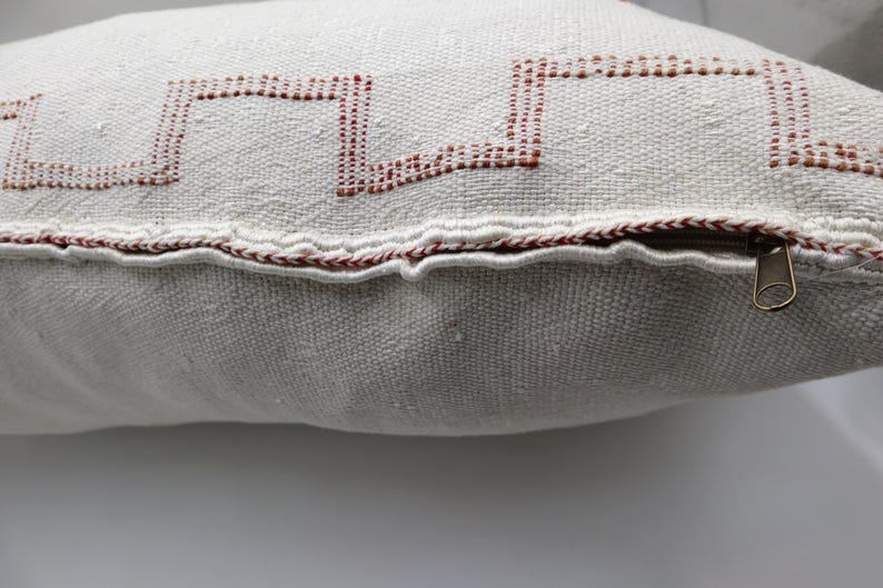 May include: White pillow with a red geometric design and a zipper closure.