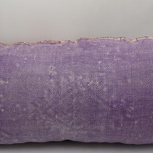 Puede incluir: Una almohada larga y rectangular de color morado con un sutil patr&oacute;n texturizado. La almohada tiene un dise&ntilde;o simple y sobrio y est&aacute; hecha de una tela suave y c&oacute;moda.