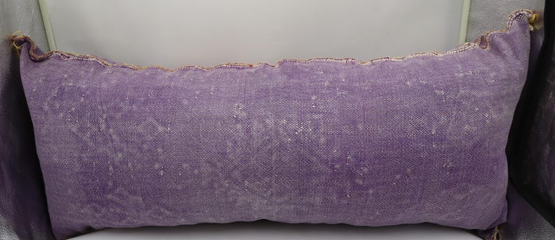 Puede incluir: Una almohada larga y rectangular de color morado con un sutil patr&oacute;n texturizado. La almohada tiene un dise&ntilde;o simple y sobrio y est&aacute; hecha de una tela suave y c&oacute;moda.