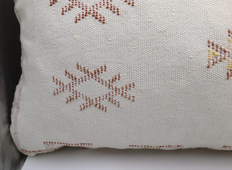 May include: White throw pillow with a brown and yellow geometric pattern.