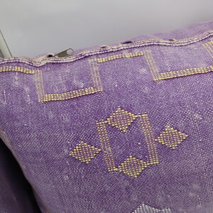 Puede incluir: Coj&iacute;n de tiro morado y dorado con cierre de cremallera. El coj&iacute;n tiene un dise&ntilde;o geom&eacute;trico con un patr&oacute;n de diamante.