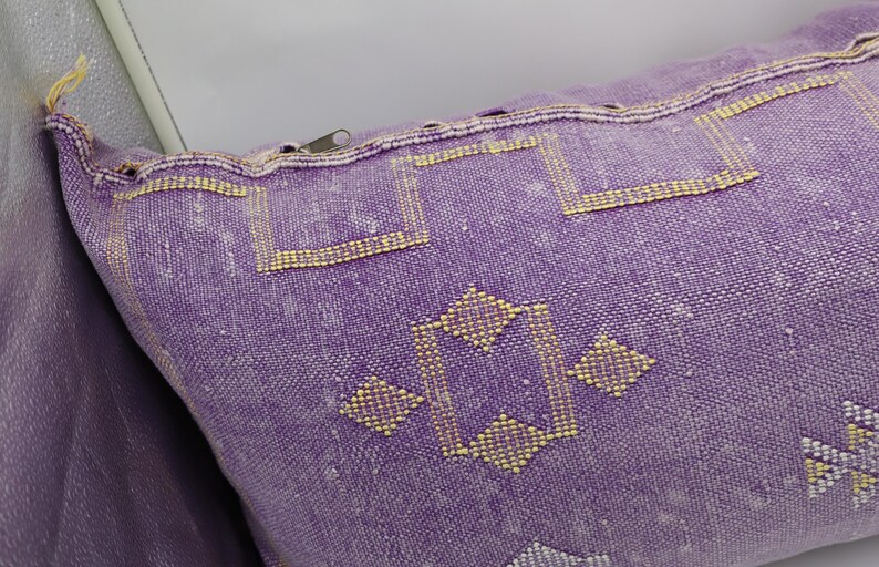 Puede incluir: Coj&iacute;n de tiro morado y dorado con cierre de cremallera. El coj&iacute;n tiene un dise&ntilde;o geom&eacute;trico con un patr&oacute;n de diamante.