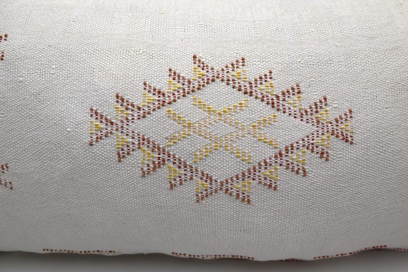 May include: White pillow with a brown and yellow geometric pattern embroidered on the front.