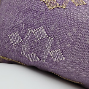 Puede incluir: Coj&iacute;n de tiro morado con un patr&oacute;n geom&eacute;trico blanco y amarillo.