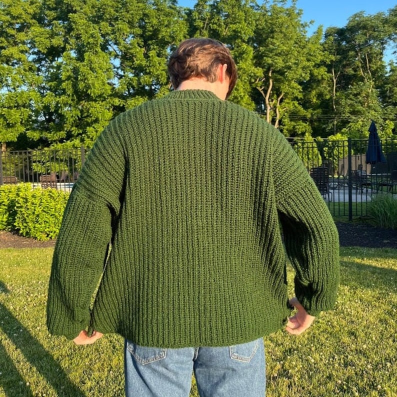 K&ouml;nnte beinhalten: Ein dunkelgr&uuml;ner Strickpullover mit Rippenstruktur. Der Pullover hat lange &Auml;rmel und eine lockere Passform.