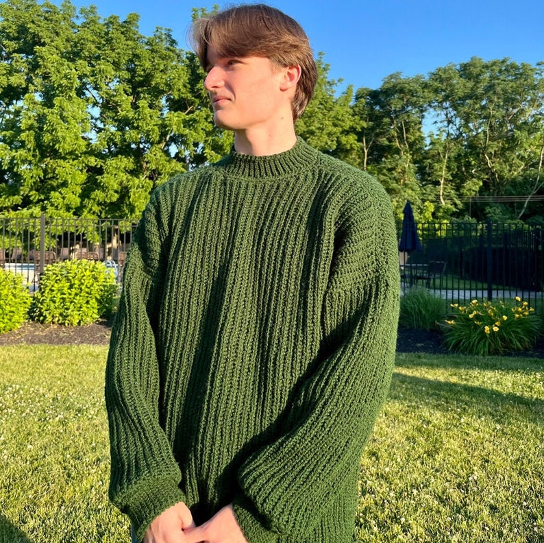 K&ouml;nnte beinhalten: Ein dunkelgr&uuml;ner Strickpullover mit hohem Kragen und langen &Auml;rmeln.