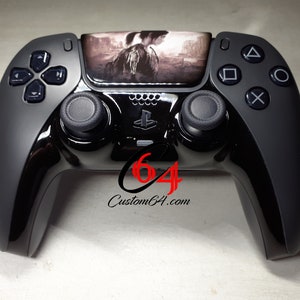 Puede incluir: Un mando de PlayStation 5 DualSense negro con una piel personalizada que presenta a una mujer en un paisaje oscuro y desolado. El mando tiene un diseño en blanco y negro con el logotipo de PlayStation y el texto "Custom64.com".