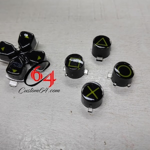 May include: Black controller buttons with green symbols, including a cross, circle, square, triangle, and directional pad. The text "Custom64.com" is also visible.