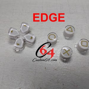 Könnte beinhalten: Ein Set aus weißen und transparenten Controller-Tasten mit goldenen Symbolen, bestehend aus einem Steuerkreuz und vier einzelnen Aktionstasten mit Dreieck-, Kreis-, Quadrat- und Kreuz-Symbolen. Der Text EDGE ist in Rot und Custom64.com in Schwarz gedruckt.