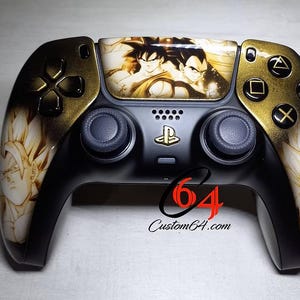 May include: Custom black and gold video game controller with Dragon Ball Z characters. The controller has gold accents on the buttons and directional pad. The centre features the PlayStation logo and the text "Custom64.com".
