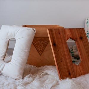 a wooden box with a cutout on the lid, placed on a white furry surface.