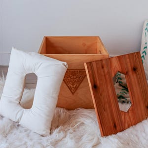a wooden box with a cutout on the lid, placed on a white shag rug.