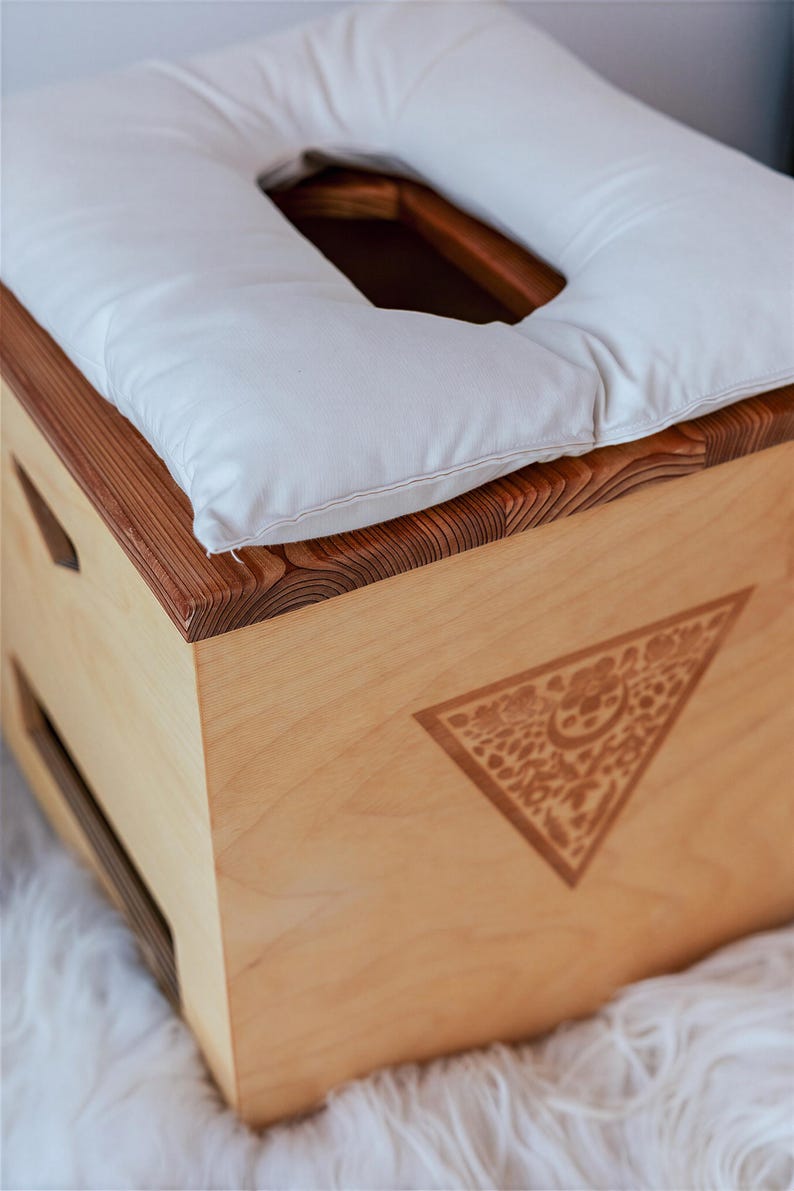 A wooden box with a white pillow on top, placed on a white furry surface.