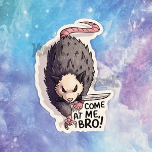 May include: A sticker featuring an illustrated opossum with a knife, and the text "COME AT ME, BRO!". The opossum is gray with a pink tail and is set against a blue and purple galaxy background.