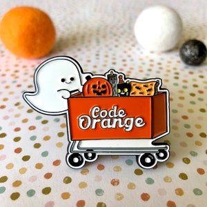 May include: A white ghost holding a small orange shopping cart filled with Halloween treats. The cart has the words "Code Orange" printed on the side.