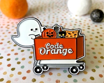 May include: A white ghost holding a small orange shopping cart filled with Halloween treats. The cart has the words "Code Orange" printed on the side.