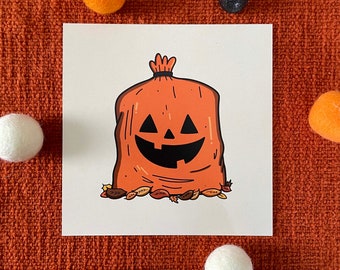 May include: A square print featuring a cartoon orange leaf bag with a carved jack-o'-lantern face. The bag is filled with leaves and has a smiling face. The print is on a white background, surrounded by orange and white decorative balls.