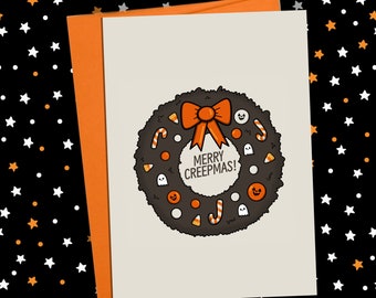 May include: A Halloween-themed greeting card with an orange envelope. The card features a black wreath with candy corn, candy canes, and ghost and jack-o'-lantern illustrations. The text "MERRY CREEPMAS!" is in the center of the wreath.