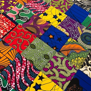 May include: A patchwork quilt with a variety of colorful fabrics. The quilt is made up of squares of different colors and patterns, including red, yellow, blue, green, and purple. The quilt is a great example of African wax print fabric.