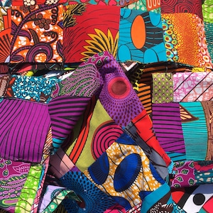 May include: A vibrant patchwork quilt composed of numerous fabric squares in a variety of colors and patterns. The quilt features bold hues of red, purple, orange, and blue, with geometric and floral designs. The quilt is a handmade textile.