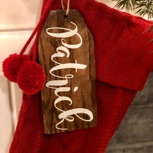 May include: A red knitted stocking with a wooden tag that says "Patrick" in white lettering.