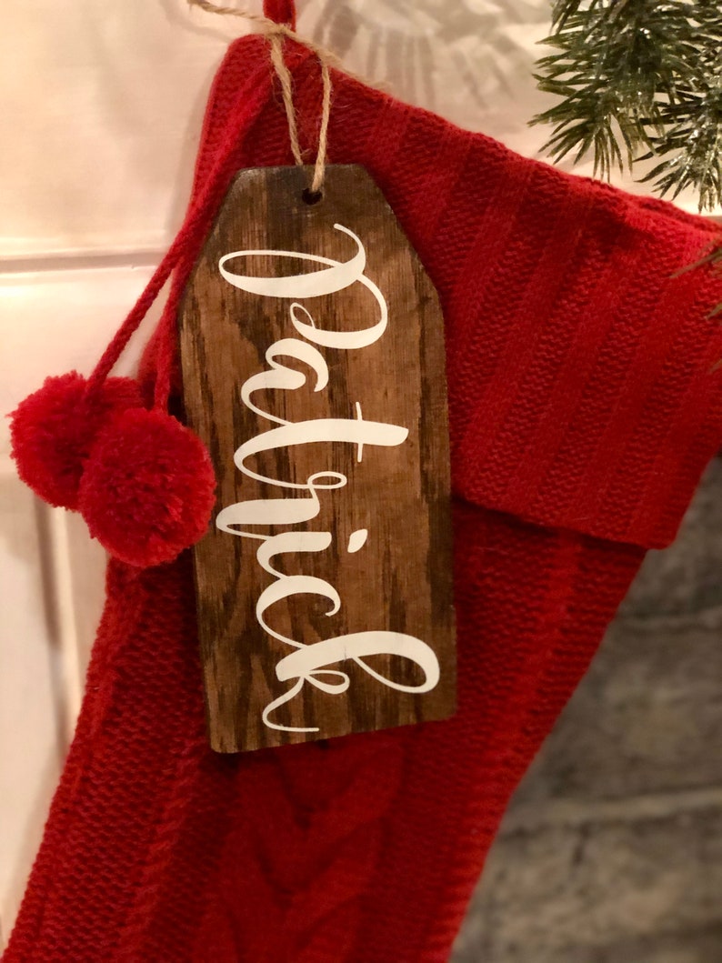 May include: A red knitted stocking with a wooden tag that says "Patrick" in white lettering.
