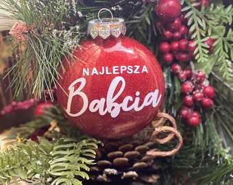 Könnte beinhalten: Roter Glitzer-Weihnachtsbaumschmuck mit dem Text "NAJLEPSZA Babcia" in weißen Buchstaben.