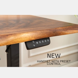 May include: A black electric standing desk control panel with buttons for up, down, memory presets, and a stop button. The text "NEW HANDSET WITH PRESET CONTROL" is displayed below the panel.
