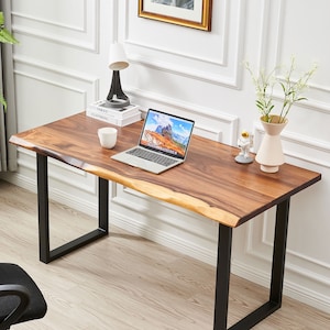 Pode incluir: Uma escrivaninha de madeira com tampo de borda viva e pernas de metal preto. Um laptop, uma x&iacute;cara, uma l&acirc;mpada e um vaso com flores est&atilde;o sobre a escrivaninha.