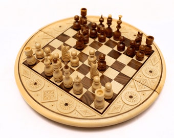 May include: A wooden chess set with brown and white pieces on a wooden board with intricate carvings. The board is folded in half and has a round shape.