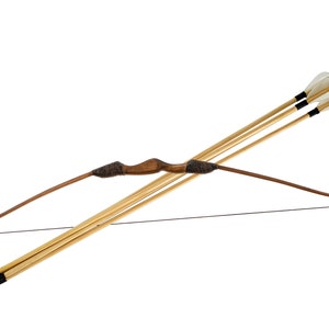 May include: A traditional wooden bow with a dark brown grip and limbs, strung with a black bowstring. Three arrows with white fletching and black tips are positioned alongside the bow. The arrows and bow are made of wood.
