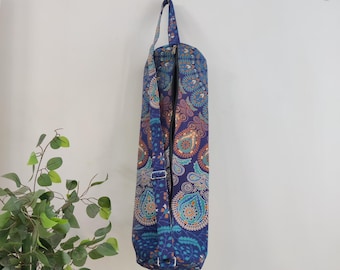 May include: A blue yoga mat bag with a colorful paisley pattern. The bag has a zipper closure and an adjustable shoulder strap.