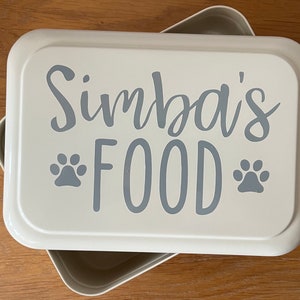 May include: White rectangular food storage container with a grey lid. The lid has the text "Simba's FOOD" with two paw prints on either side of the word "FOOD".