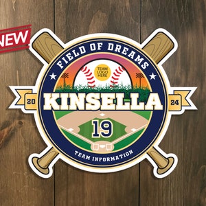 Könnte beinhalten: Ein blauer und weißer runder Aufkleber mit einem Baseballfeld, zwei gekreuzten Baseballschlägern und dem Text "FIELD OF DREAMS KINSELLA 19 TEAM INFORMATION" mit einem gelben Stern und einem Banner mit dem Text "20 24".