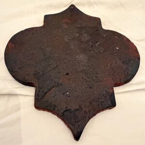 Black Rub Terracotta Alhambra Tile featuring a dark, rustic finish and a distinctive Moroccan-inspired shape