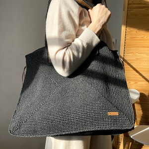 May include: A large black crocheted tote bag with leather straps and a brown leather tag that says "remarkable".